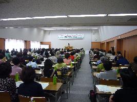 写真：満員の会場で講演する行列のできる法律相談所-住田弁護士